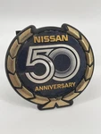 Vintage Nissan 50TH Anniversary Emblem Badge 3.5 Inches Wide With Studs. Fixed Price $125.00.